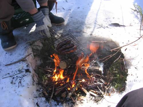 More sausages cooking on the fire.